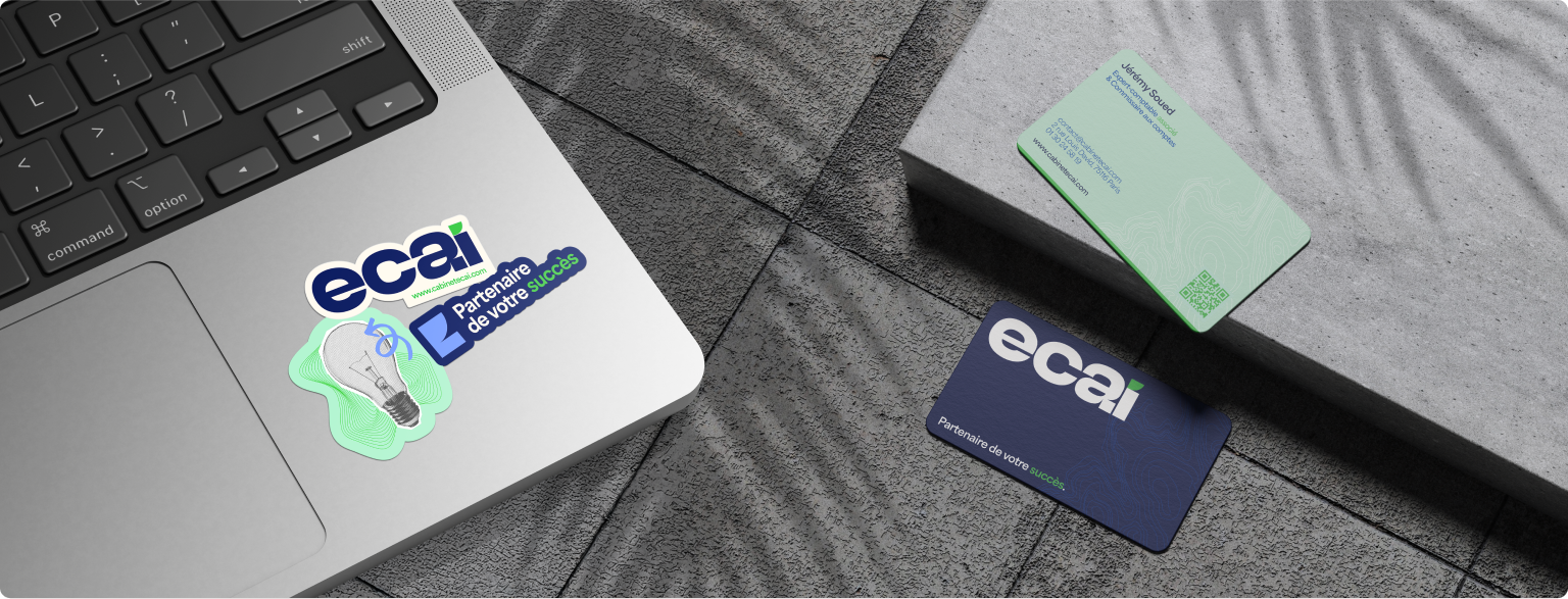 Cartes de visite ECAI bicolores et sticker logo sur laptop, supports print du rebranding.
